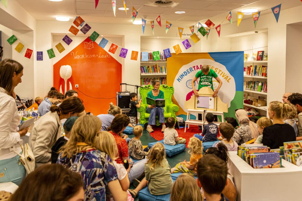 Een kring met kinderen die worden voorgelezen uit een boek, tijdens een voorgaande editie van Kletskoppen Festival.